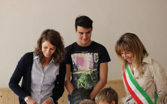 Il sindaco e due giovani del Rotary osservano i bambini giocare col materiale appena ricevuto